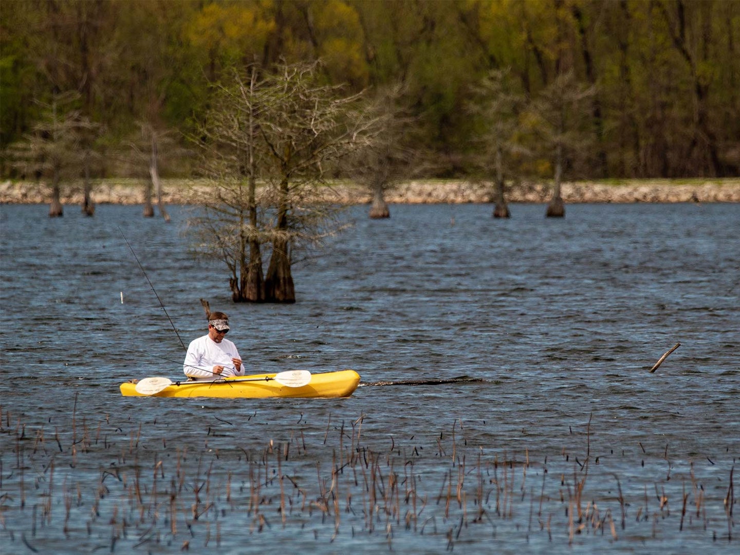 A man rides in a kayak across a lake using the best fishing motor.