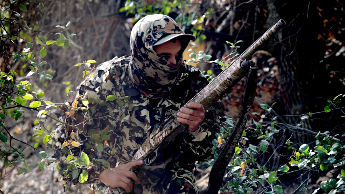 Hunter in the woods holding Mossberg turkey shotgun