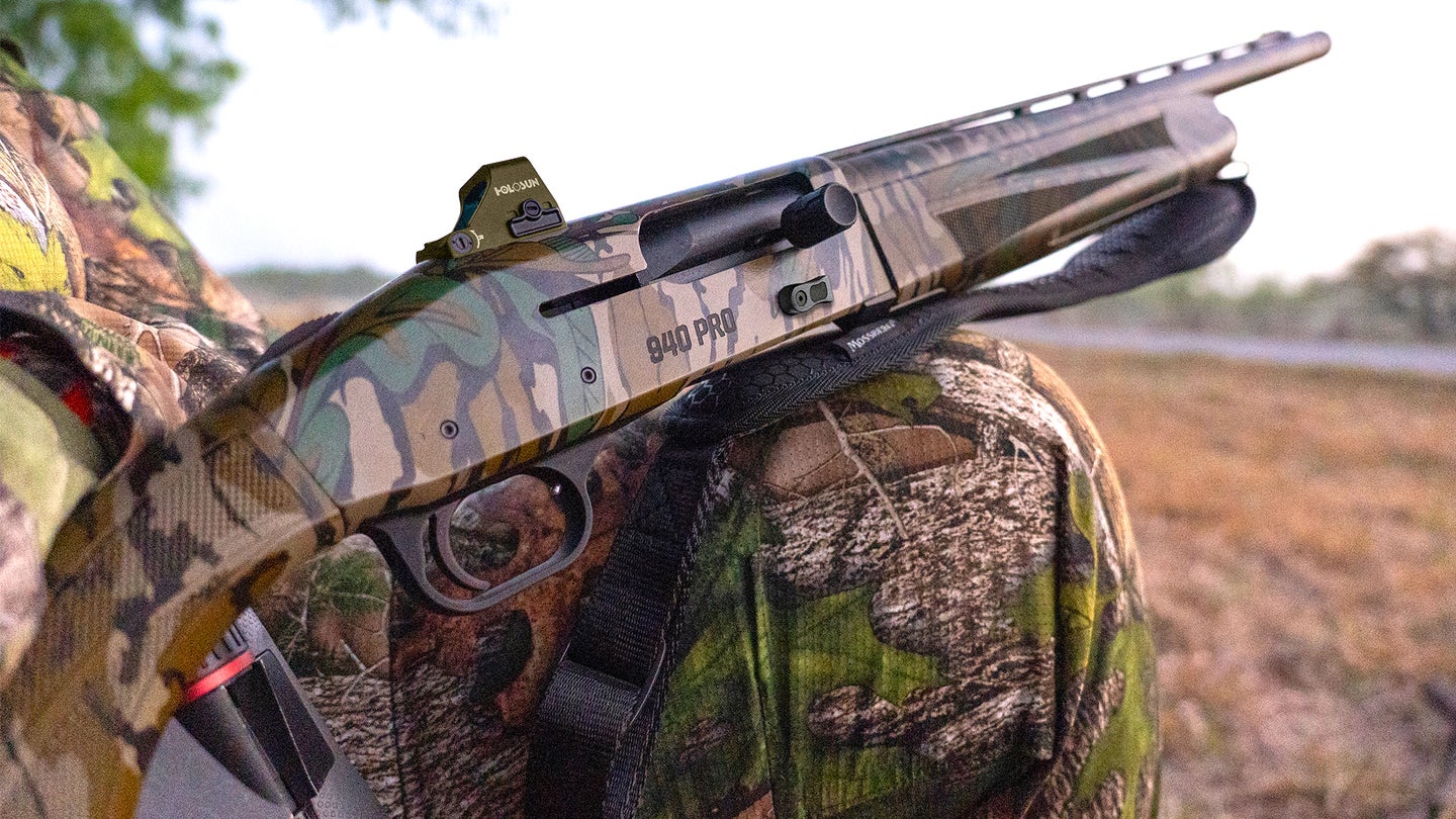 A Mossberg 940 Pro shotgun resting on a hunter's knee.