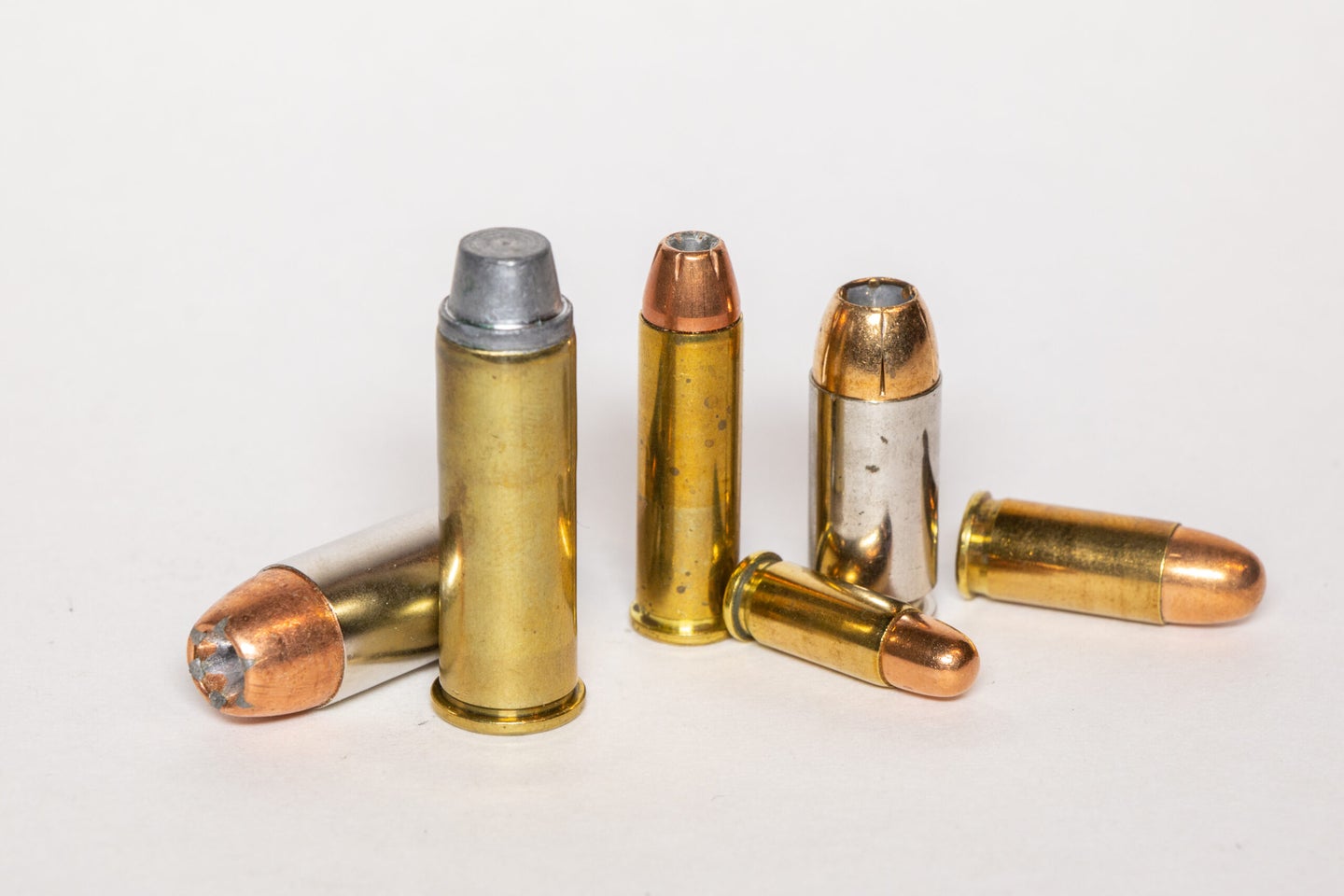 Six handgun cartridges on a white background.