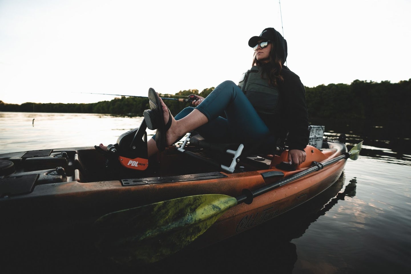 Woman on pedal kayak holding a fishing rod.