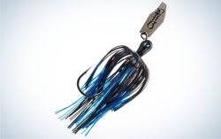 A fish chatterbait with many blue and black threads and a metal clip in it.