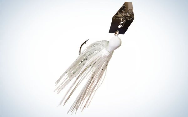 A fish bait with many white threads and a black metal clip in it.