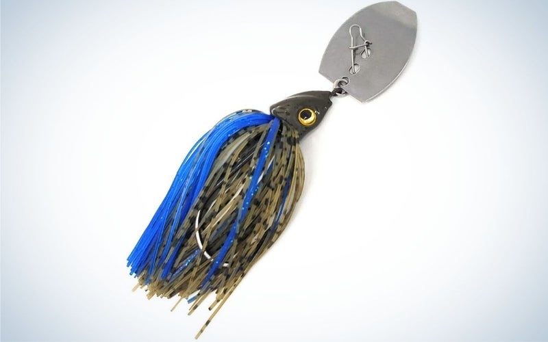 A fish bait with many blue and black threads and a metal clip in it.