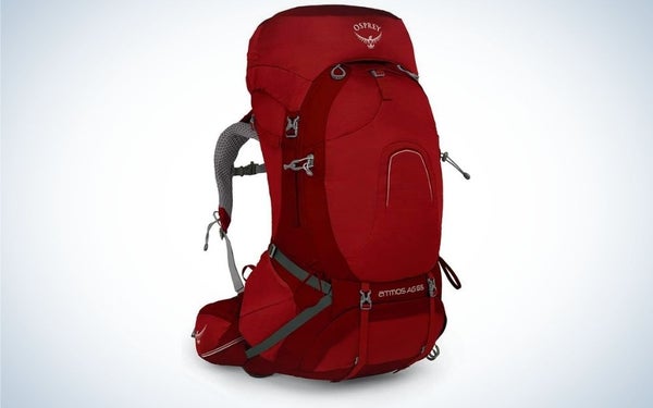 A backpack with a bright cherry color and with gray arms from the back and a large pocket with a zipper in front of it.