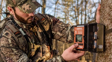 A deer hunter shows where to mount a trail camera