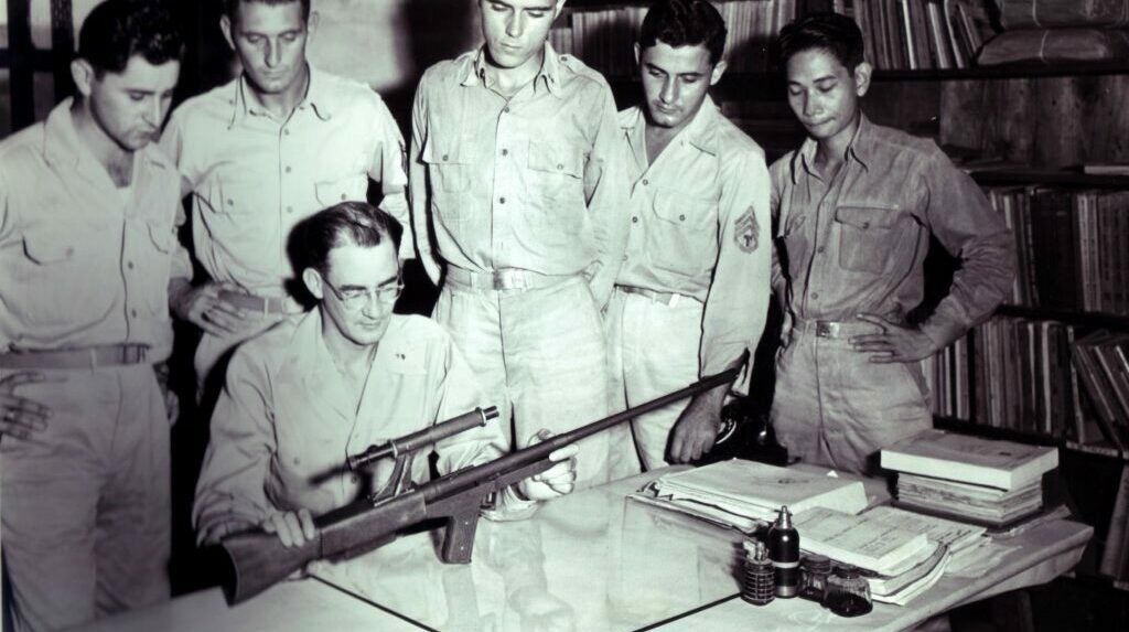 group of soldiers examining a prototype rifle.