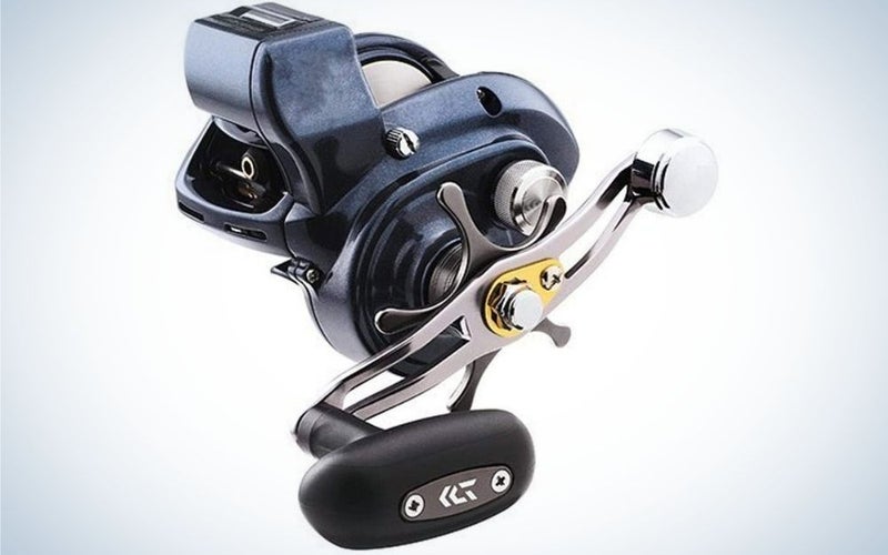 A spincast reel all black as a small intricate machine with a silver lever located on the side of the machine.