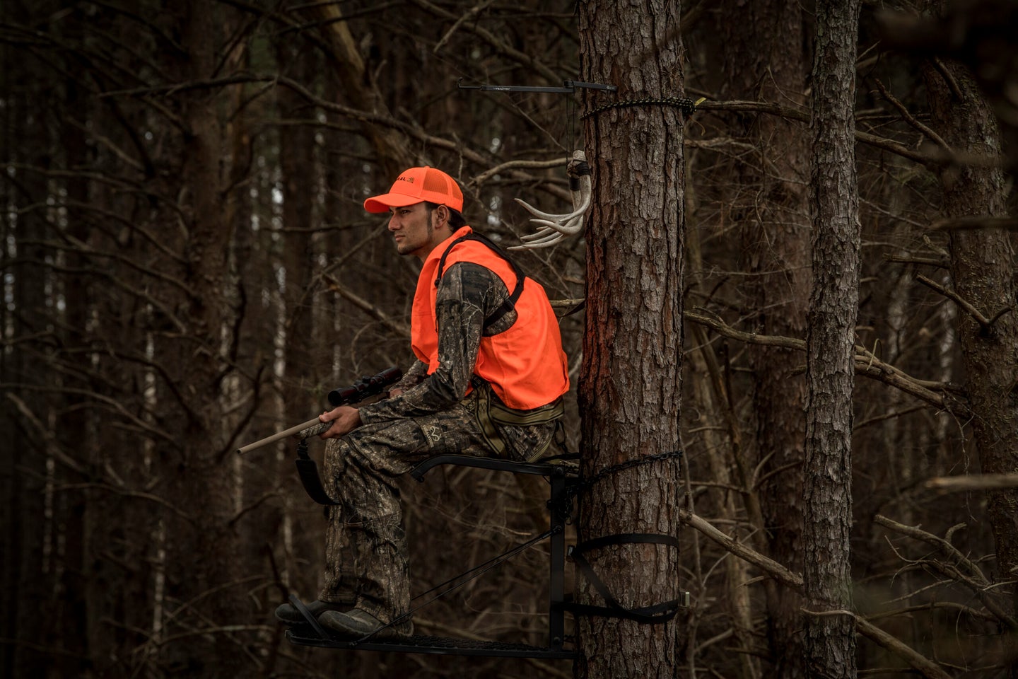 rifle hunter sitting in a tree stand