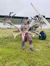 Woman stands with caribou antlers in front of small crop jet