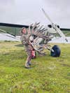 Woman stands in front of propeller plan with caribou antlers