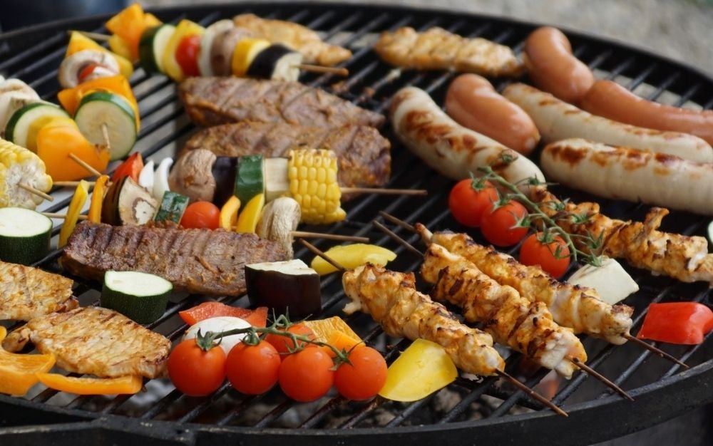 Meat and vegetables on a charcoal grill.