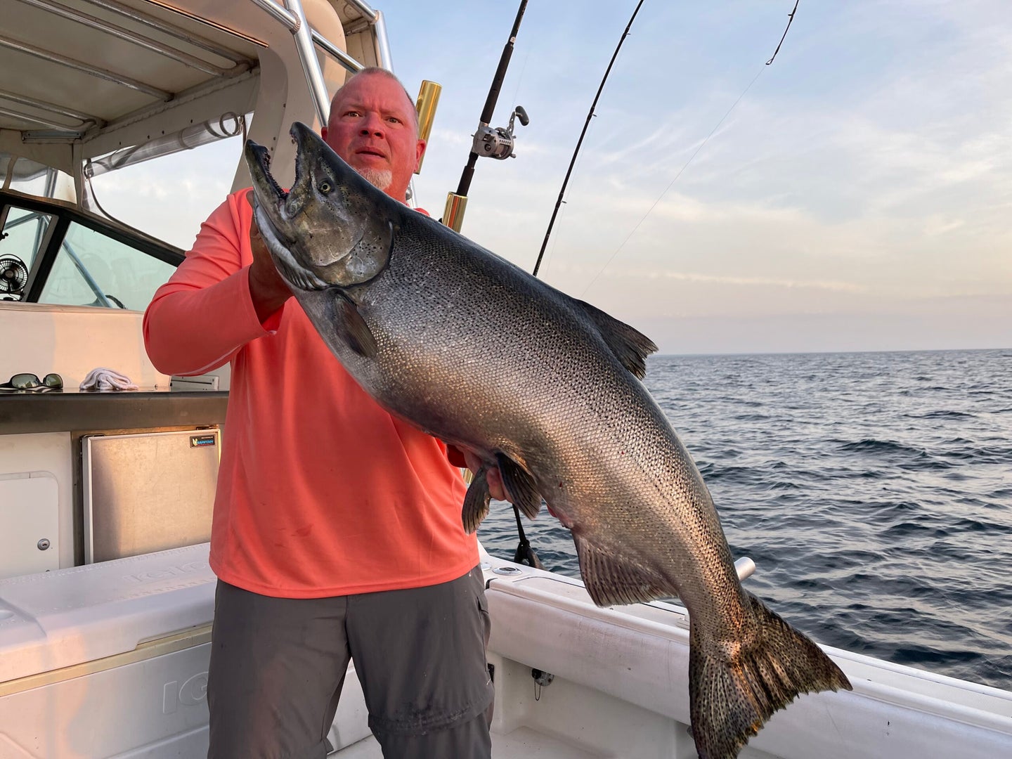 man holds large salmon aboard boat
