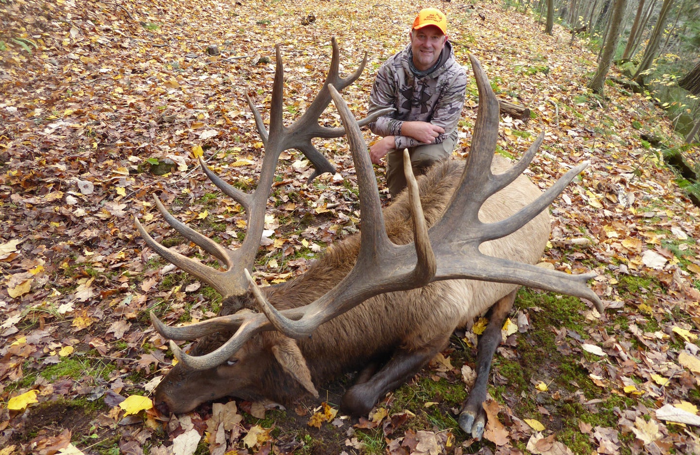 Man sitting on the ground with the Pennsylvania record bull elk.