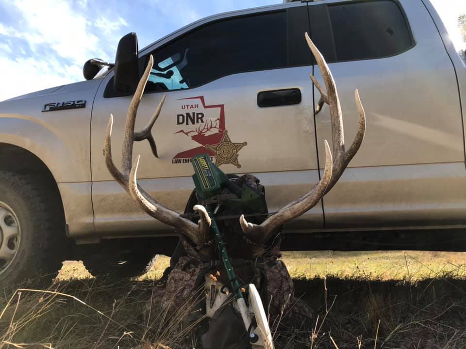 a backpack with a deer rack in front of a Utah DWR pickup truck