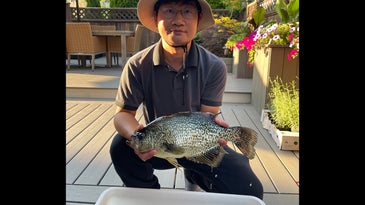 Man with straw hat poses with large black crappie fish