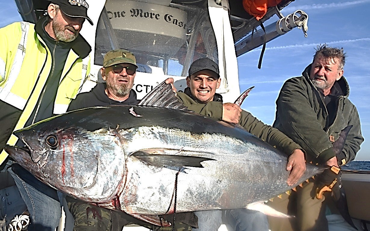 group of anglers hold massive bluefin tune