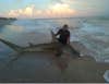 man with large hammerhead shark on shore