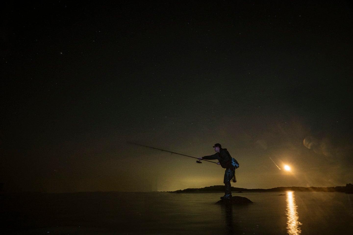 A surf fisherman casts into the night.