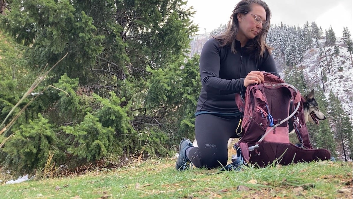 Female hiker wearing Sitka Core base layers while packing her backpack
