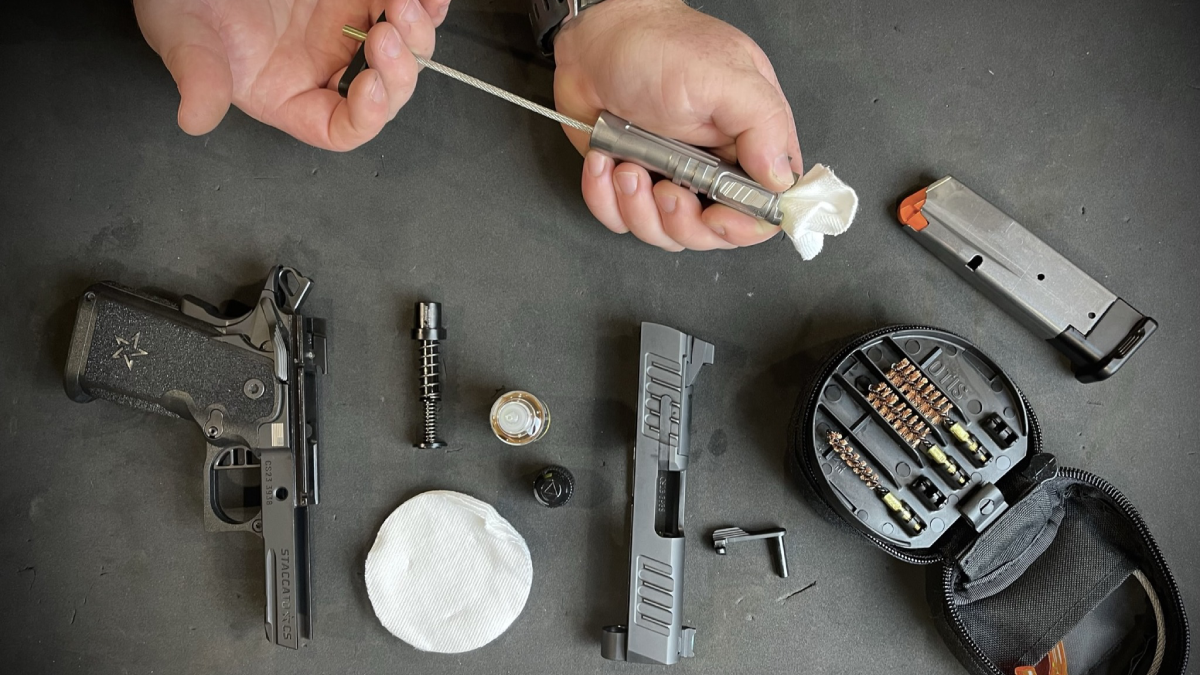 Man using Otis gun cleaning kit to clean pistol