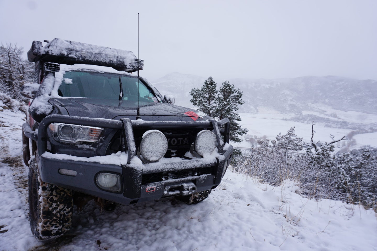 Off-road truck parked on a mountain in the snow.