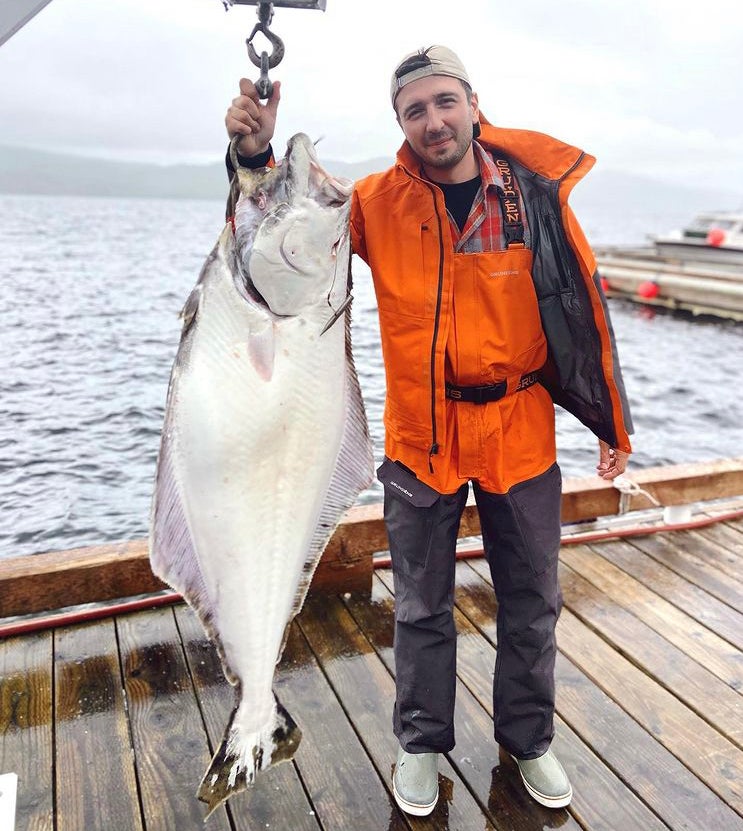 F&S editor Matthew Every standing on a dock with an 80-pound halibut.