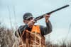 a bird hunter aiming a shotgun.