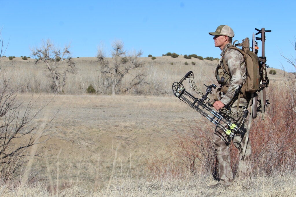A hunter hikes into the field with a tree stand