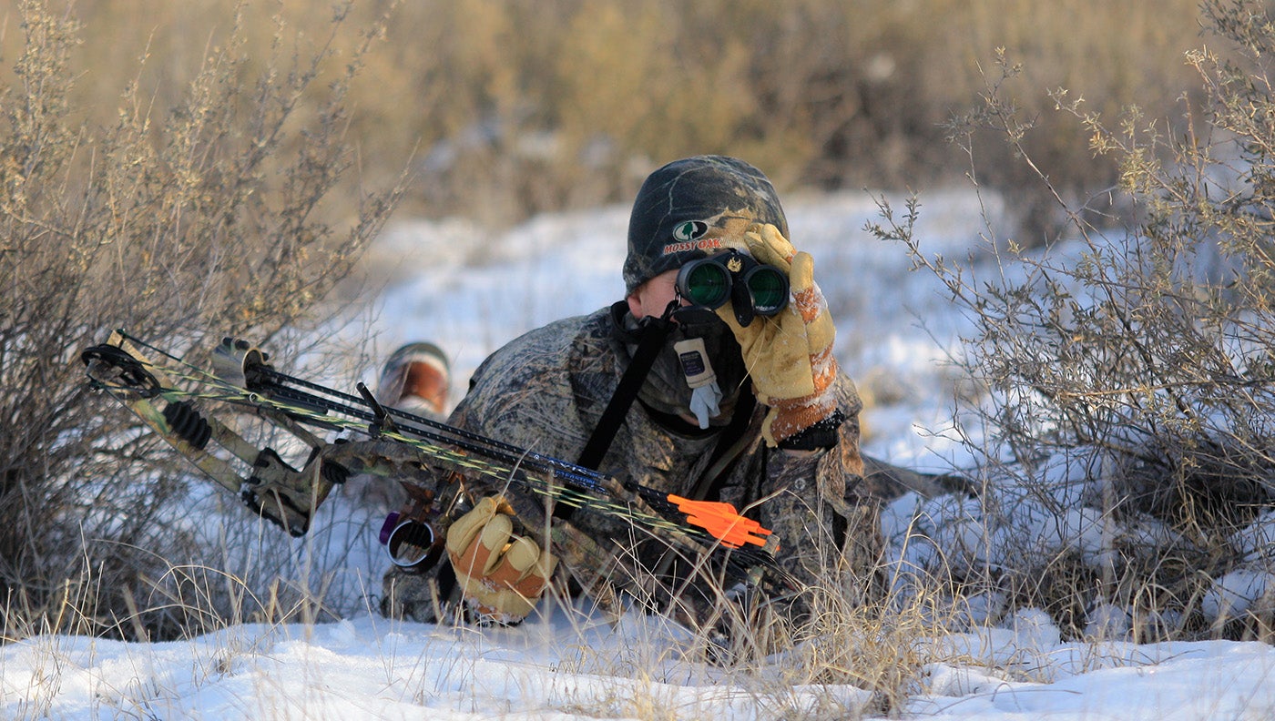 a hunter crawls with bow while stalking mule deer