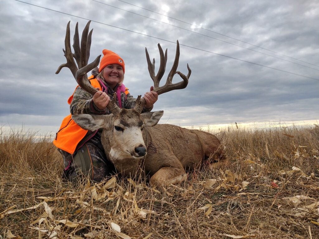 young female hunter takes grip-and-grin with big mule deer buck