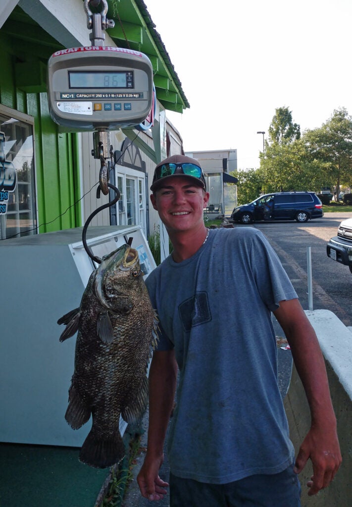 young angler poses next to record tripletail