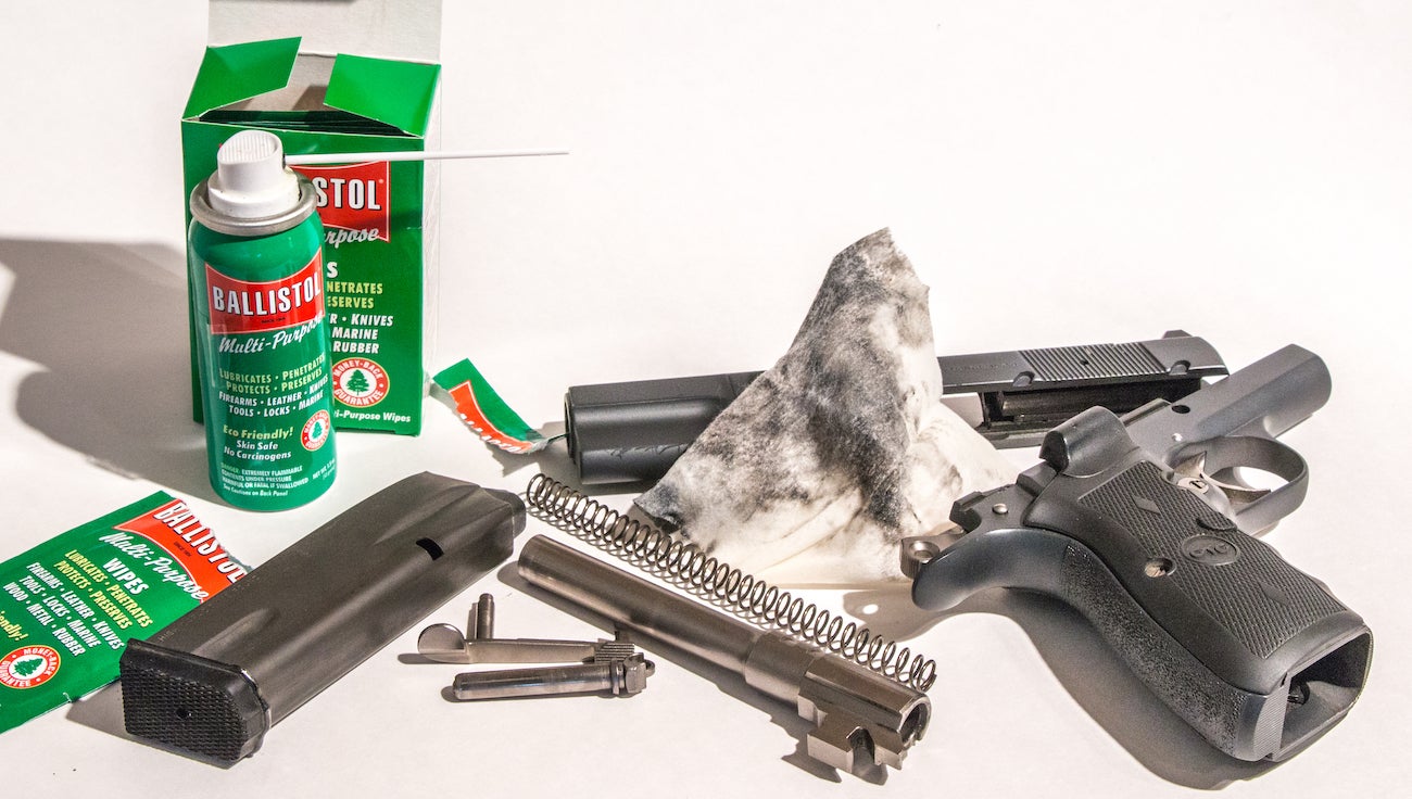 Gun cleaning solvents and rags with a handgun on a table.