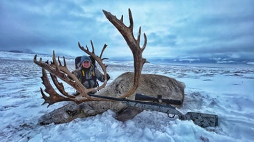 Hunter poses with dead caribou with giant rack