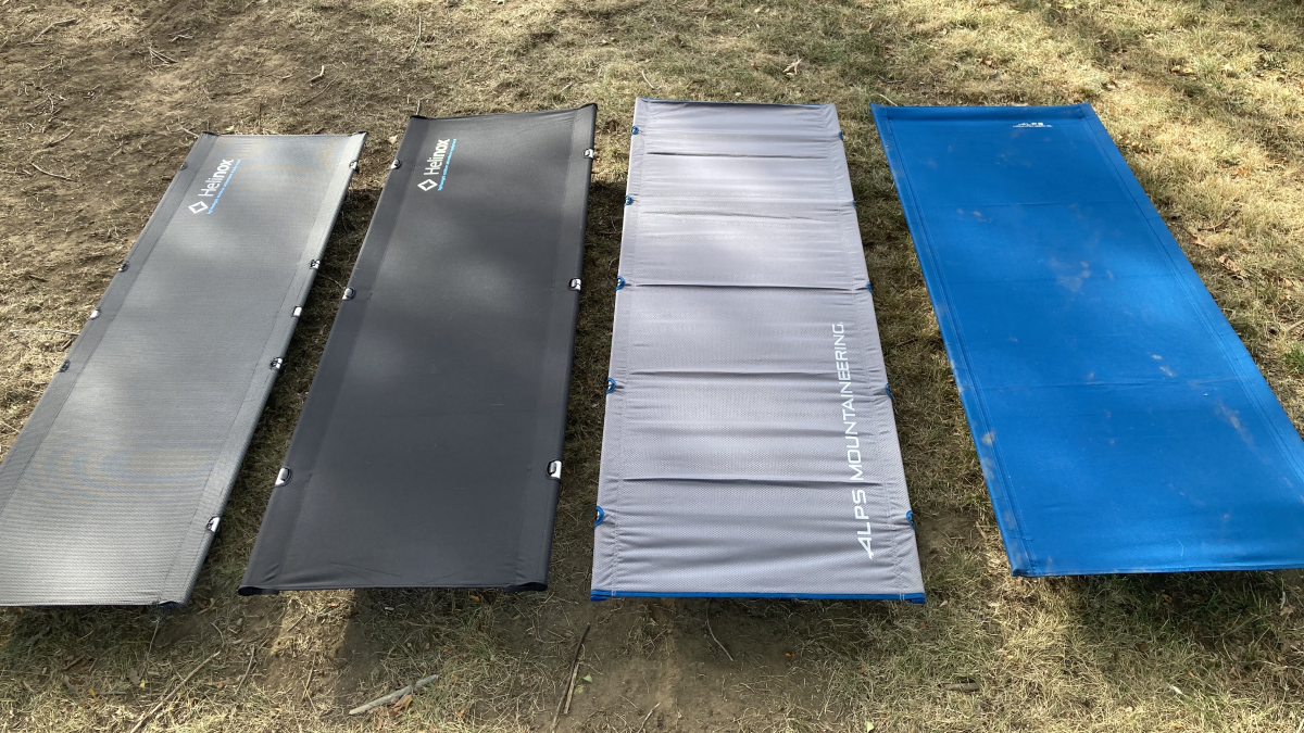 Four portable camping cots set up on grass