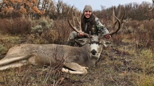 woman hunter poses with large dead mule deer