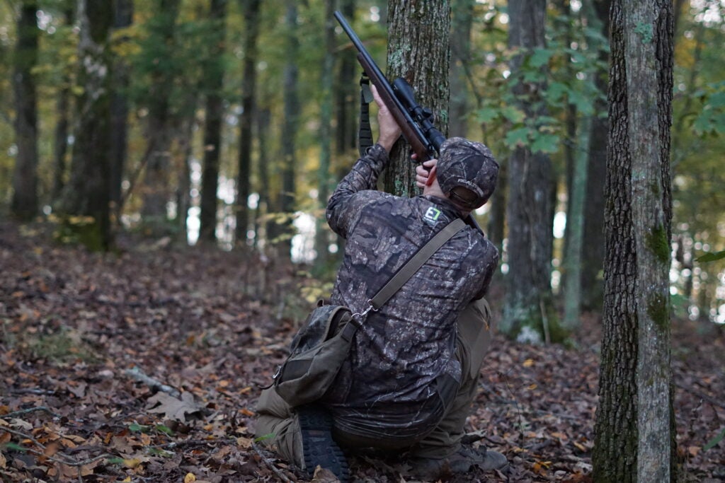 A hunter shooting a squirrel with a rifle.