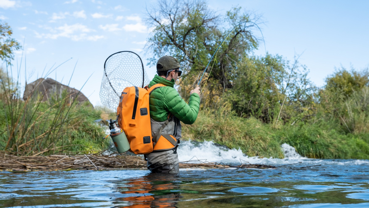 Angler fly fishing while wearing FishPond fishing backpack