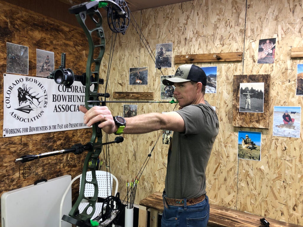 Man drawing a bow indoors.