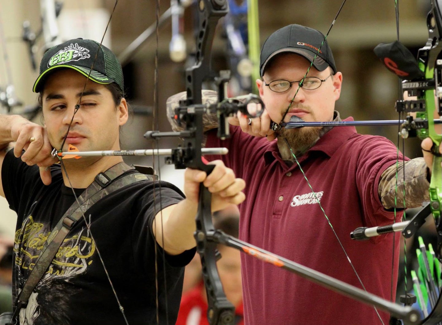 Two archers side-by-side shooting in an indoor archery league.