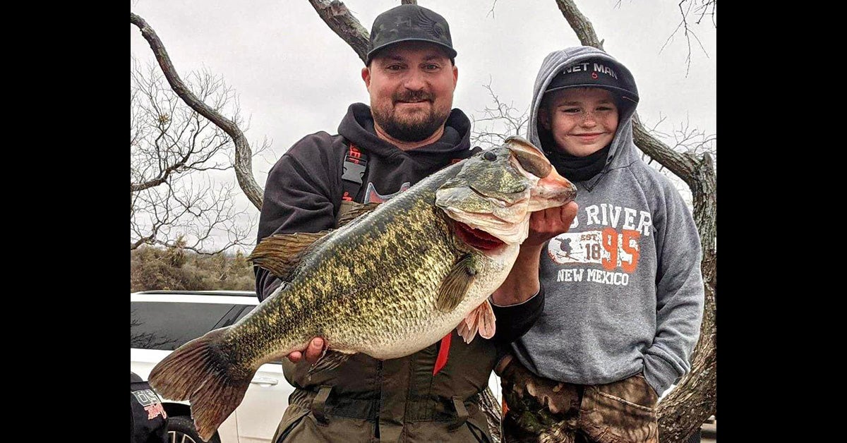 man and boy pose for camera with big largemouth bass