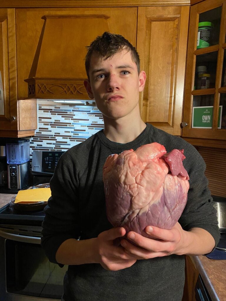 boy holds large heart in kitchen