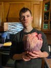 boy holds large heart in kitchen
