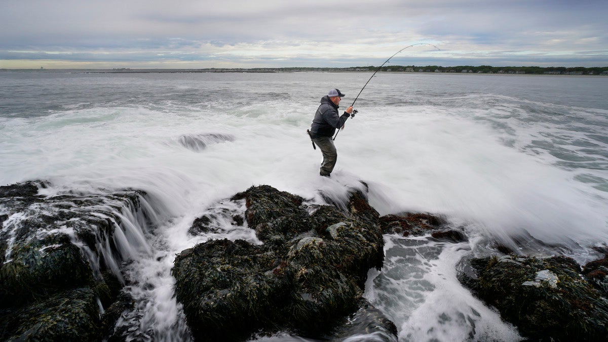 KENNEBUNKPORT, ME - JUNE 9: Paul Korenkiewicz tries to land a striper as a wave crashes over rocks where he is fishing off the coast of Kennebunkport on Friday, June 9, 2017.
