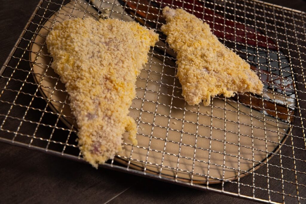 Breaded fish fillets on a rack.
