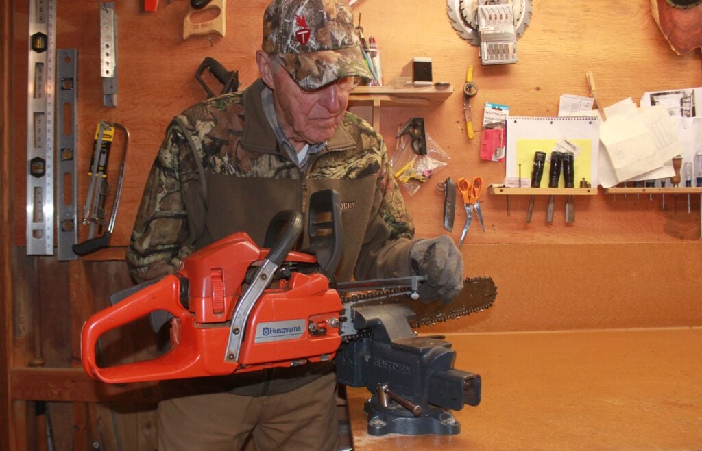 Author showing how to sharpen a chainsaw with a guide 