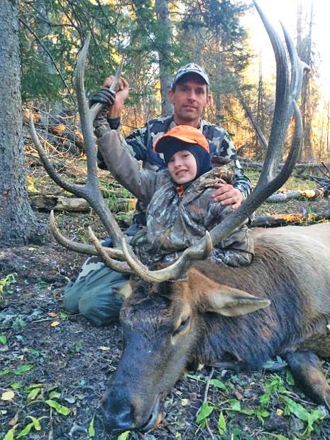 man and son pose with large dead bull elk