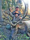 man and son pose with large dead bull elk