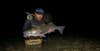 Fisherman with a striped bass at night.