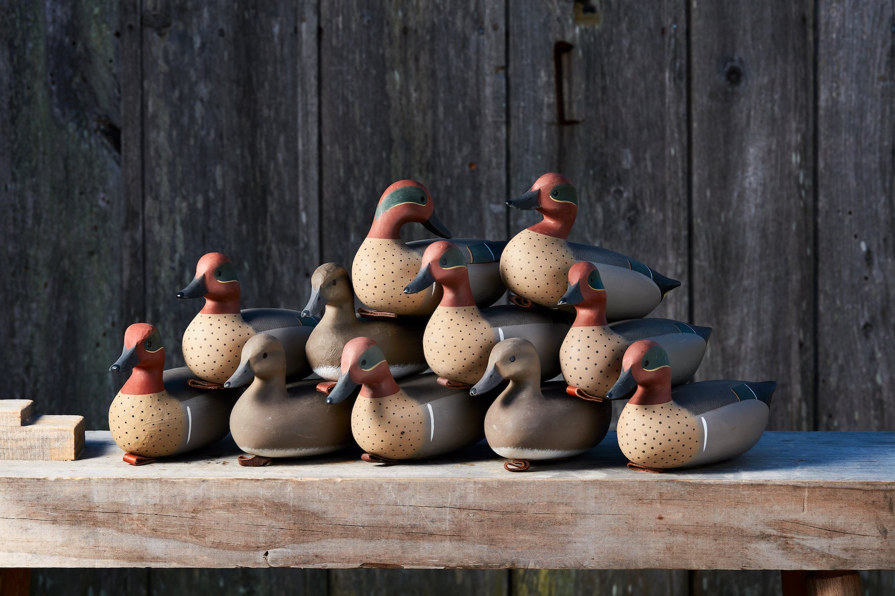 A pile of hand-carved teal decoys on a carving bench.
